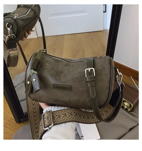 Macro detail of dark green vintage cylinder bag with wide woven strap and metal buckle