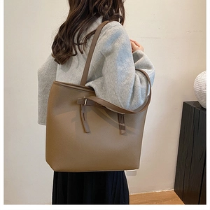 Detail of a brown textured leather tote bag showing side view and decorative buckle strap
