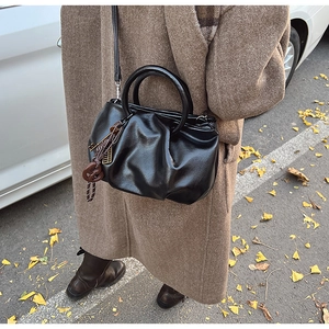 Détail d'un sac seau plissé noir vintage avec poignée ronde sur fond de rue d'automne