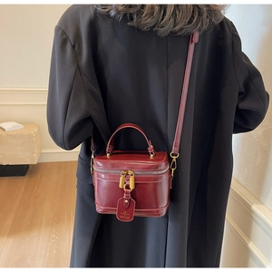Detail of wine red box bag with glossy leather texture and gold dual zipper closures