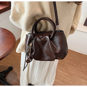 Détail du sac seau marron foncé plissé avec poignée anneau et breloque métallique