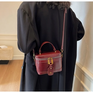 Polished deep red-brown box bag with dual zippers and brand pendant in a classic style