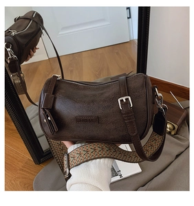 Detailed view of dark brown cylinder bag featuring vintage leather texture and wide strap