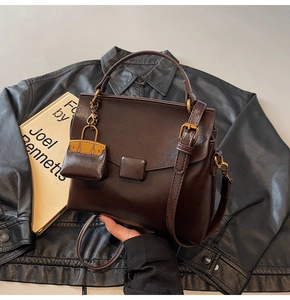 Close-up of retro brown leather shoulder bag with decorative mini pouch on a black jacket