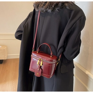Detail shot of vintage burgundy box bag with gold zippers and leather brand tag