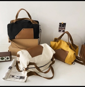 Three large canvas travel bags in black, beige, and mustard yellow with leather pockets