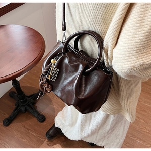 Détail du sac seau plissé marron foncé avec breloques et bandoulière réglable