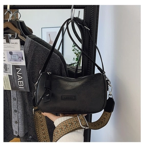 Detail of black pebbled leather crossbody bag with wide geometric woven shoulder strap