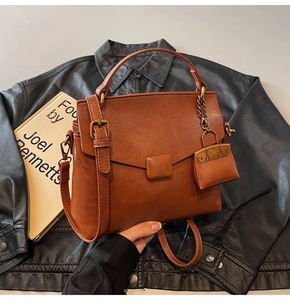Detail of vintage brown crossbody bag with adjustable strap and decorative mini pouch charm