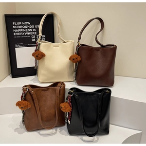 Macro view of four versatile PU leather tote bags in various colors with cute teddy charms