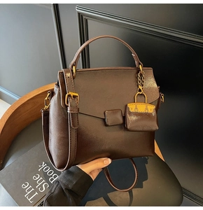 Detail of dark brown leather handbag with gold hardware and mini bag charm accessory