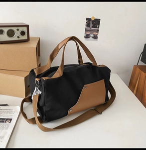 Detail of canvas travel tote with brown leather handles and adjustable shoulder strap