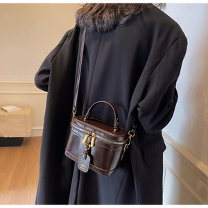 Detail of caramel leather vanity bag with gold hardware and logo tag on a chic model