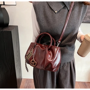 Détail du sac nuage bordeaux montrant la texture du cuir brillant et le bijou de sac