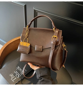 Close-up of vintage dark coffee underarm bag with glossy oil wax leather and mini charm