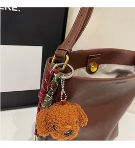 Close-up of brown leather bucket bag with teddy dog charm and gold magnetic closure