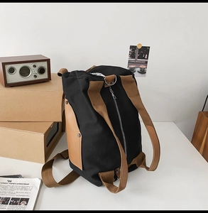 Detail view of a black canvas backpack with brown straps in a vintage office desktop setting