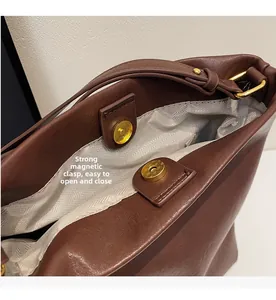 Detail of strong magnetic snap closure on premium brown leather bucket bag with gray lining