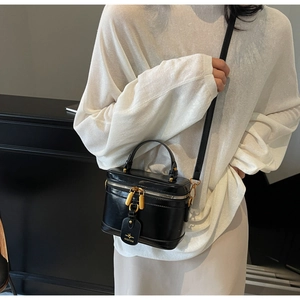 Detail of a black box bag with shiny leather texture and golden metal hardware