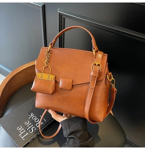 Detail of vintage brown leather handbag featuring a mini pouch charm and bronze hardware