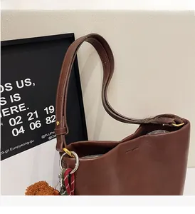 Detail of dark brown leather handbag with silver rings and plush charm accessory