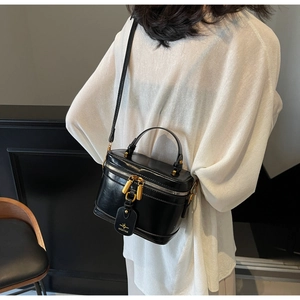 Detail of the polished black leather vanity bag with gold hardware and top handle