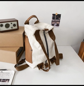 Detail view of canvas backpack on desk with adjustable straps and side leather pockets