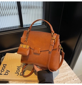 Detail view of a vintage brown leather handbag with mini charm and gold metal hardware