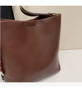 Close-up of the soft brown leather texture and stitching of the bucket tote bag