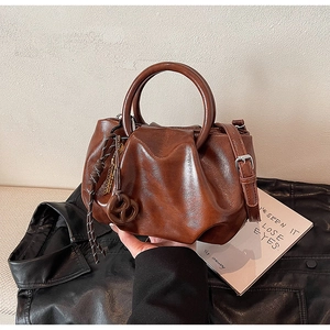 Détail d'un sac seau plissé marron vintage avec poignées rondes et décor noué