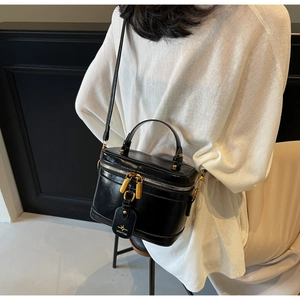 Detail of black glossy mini box bag with gold metal zippers and round handle