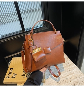Detail of retro caramel leather square bag with matching mini charm on marble surface