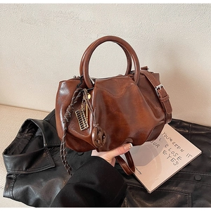 Vue détaillée du sac seau plissé marron vintage avec pendentifs en métal et deux poignées