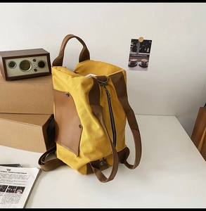 Detail view of the retro yellow canvas backpack with brown straps and large capacity