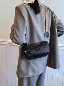 Classic black crossbody pillow bag with vintage wide woven strap and camera tag