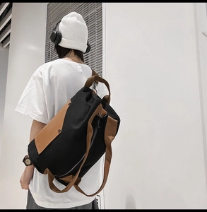 Detail showing back view of canvas travel bag with brown straps on a model in urban setting