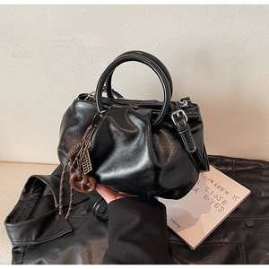 Vue détaillée d'un sac à main plissé noir brillant avec poignée ronde et pendentif chic