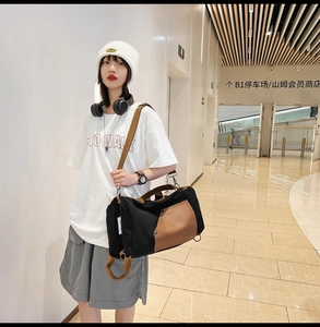 Detail of a black canvas duffel bag with brown leather accents and adjustable shoulder strap