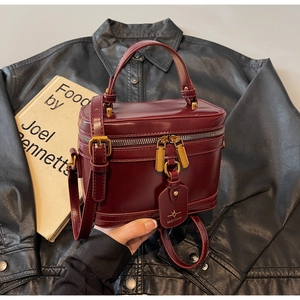 Detail of vintage burgundy box bag featuring leather texture and metallic zipper