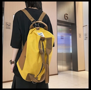 Detail of yellow canvas backpack showing durable leather straps and metal hardware