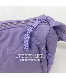 Detail of a purple quilted nylon bag featuring a smooth metal zipper and woven puller