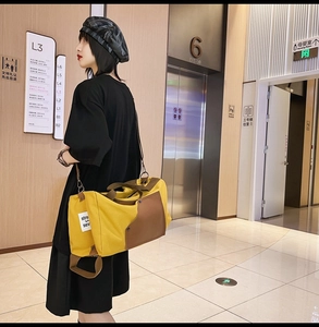 Detail of yellow canvas travel bag with leather accents and adjustable shoulder strap