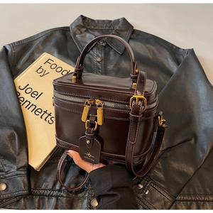 Close-up of a vintage brown box-style handbag with glossy leather and golden hardware