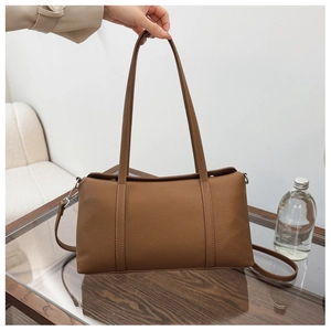 Dettaglio ravvicinato della borsa tote in pelle marrone con grana a litchi e manici