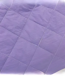 Detail of purple quilted tote bag featuring classic diamond patterns and white stitching