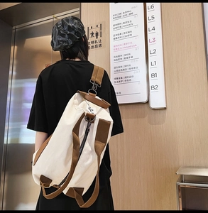 Close-up of a cream canvas travel backpack with brown straps in a modern mall setting