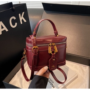 Macro shot of burgundy leather vanity box bag with gold star logo in luxury gift box