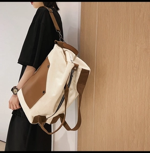 Detail of canvas travel bag featuring brown leather trim and adjustable shoulder strap