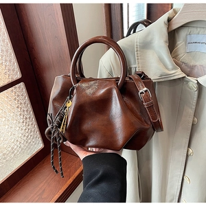 Détail du sac seau plissé marron foncé avec poignées rondes et pendentifs décoratifs