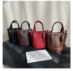 Litchi pattern leather bucket bags in black, brown, red, and beige shown on a bench
